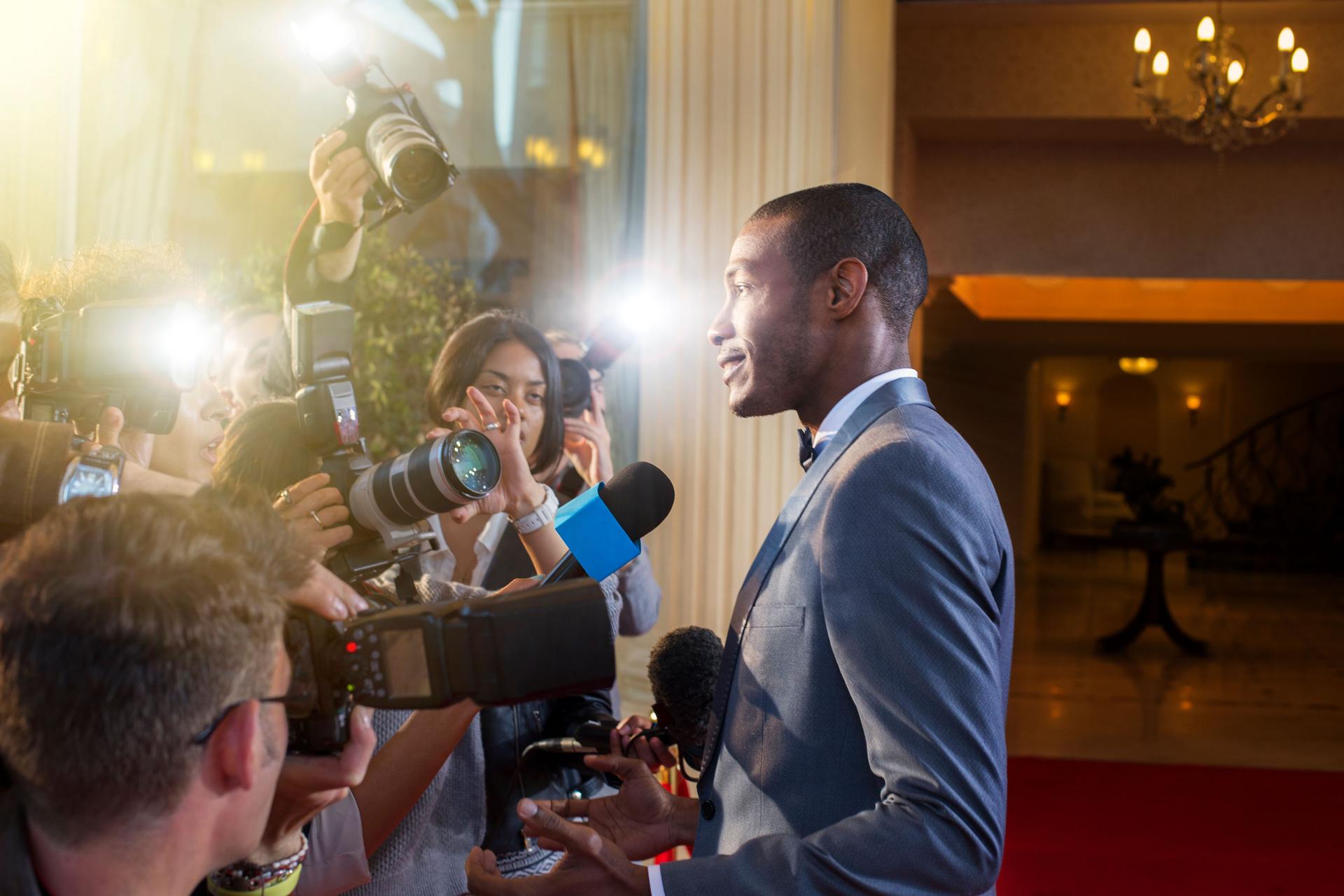 Celebrity being interviewed and photographed by paparazzi at red carpet event